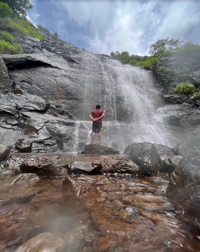Person standing beneath a large waterfall
