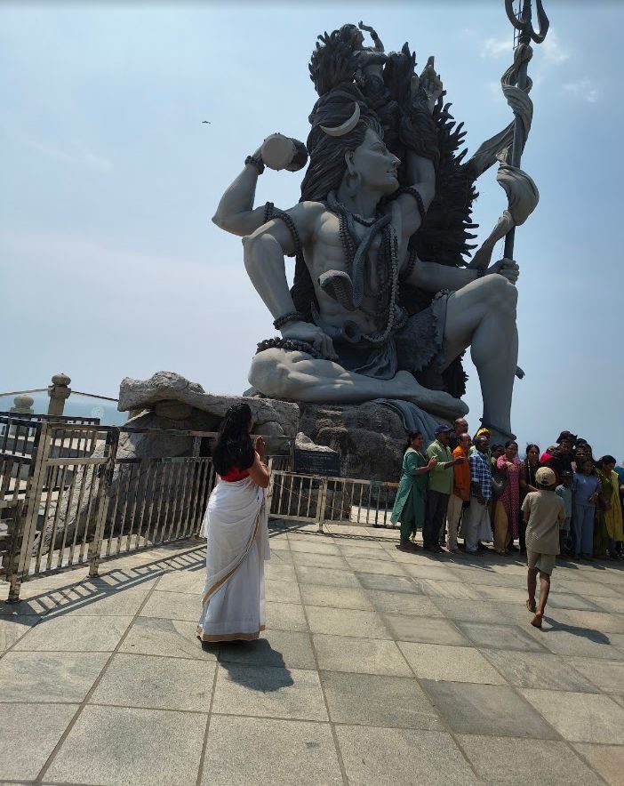 Visitor standing before a monumental Shiva statue