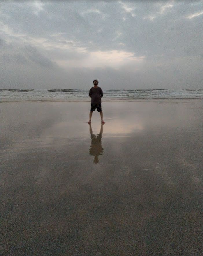 Solitary figure reflected on a wet beach