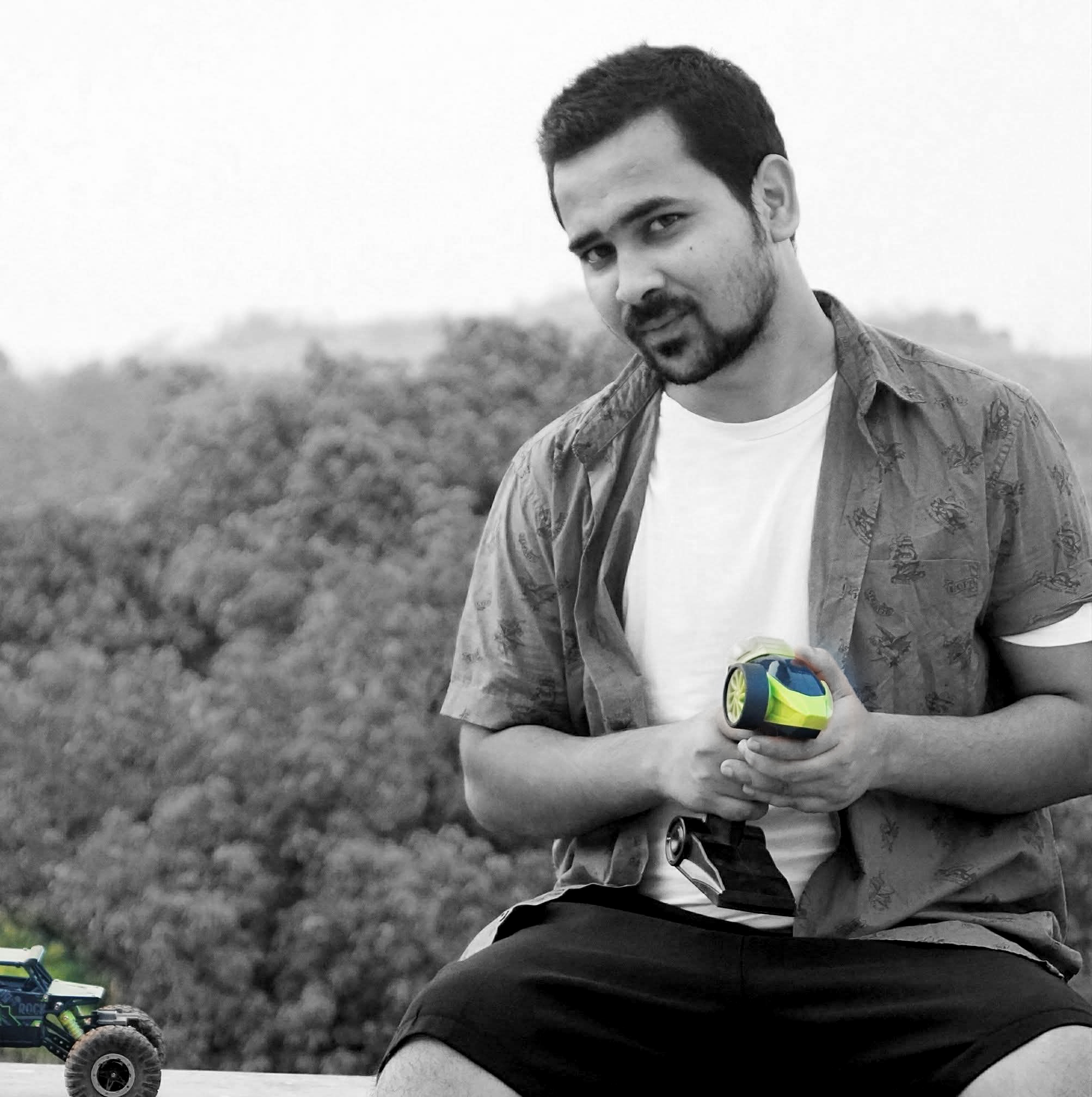Pratik Jadhav in a blue overshirt and white T-shirt, holding an RC controller
